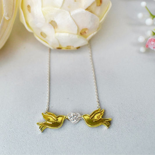 Sterling silver gold plated lovebirds are linked by each holding a sterling silver heart studded with small circonas, suspended from a sterling silver chain.