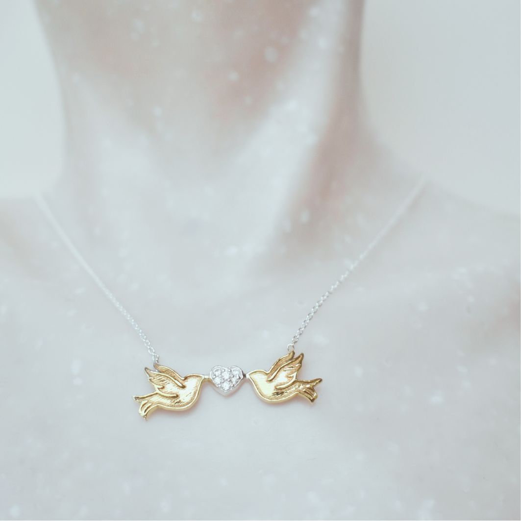 Sterling silver gold plated lovebirds are linked by each holding a sterling silver heart studded with small circonas, suspended from a sterling silver chain.
