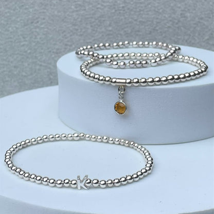 our silver initial bracelet shown with the silver beaded bracelet and birthstone bracelet