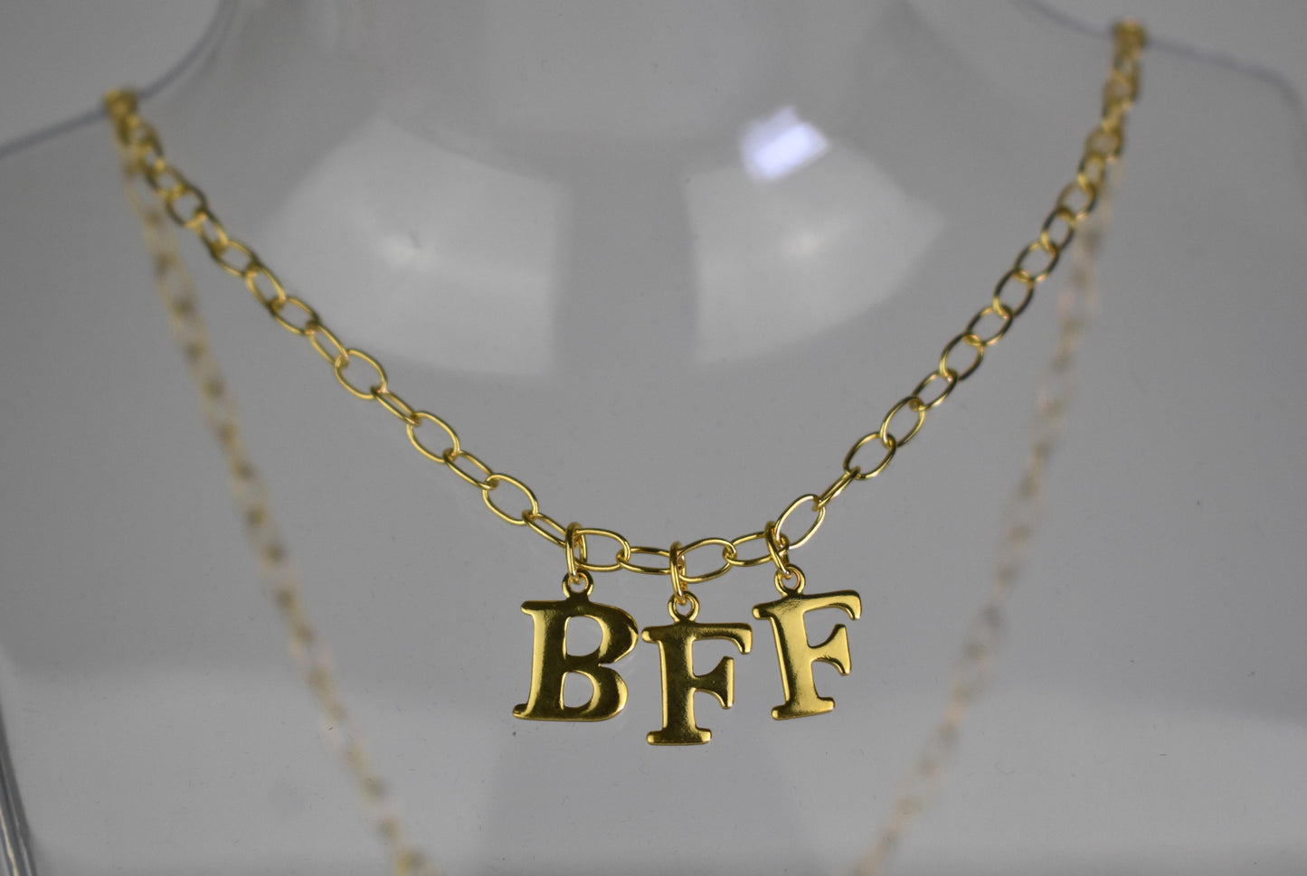 Model wears Necklace chain with and letters. Crafted with a 5.5mm link size chain in gold vermeil with serif letters spelling out BFF (Best Friends Forever). Each letter is a classic serif uppercase font.