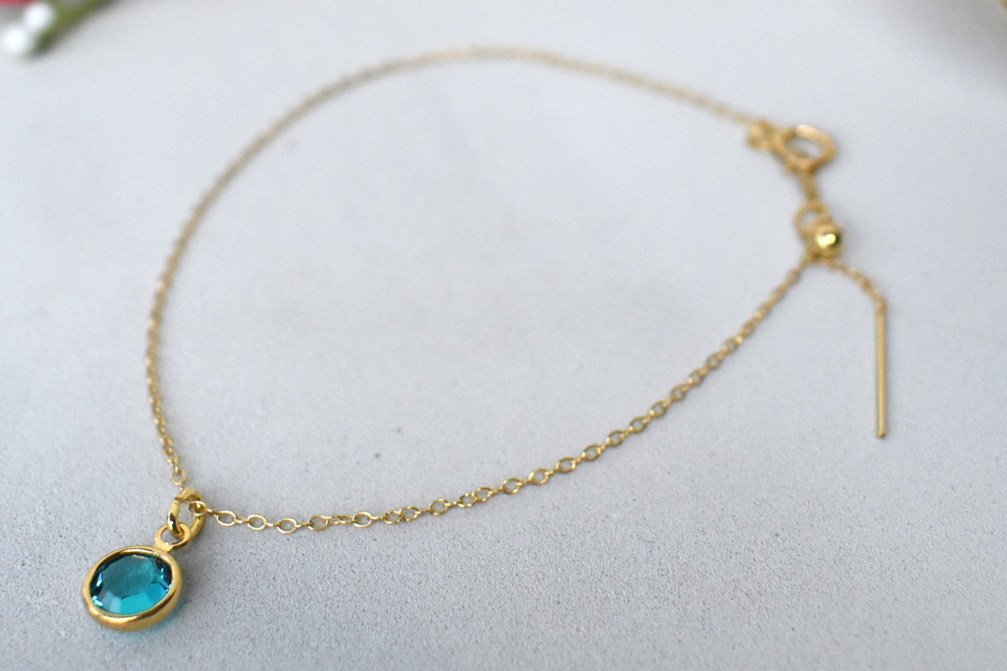 A gold filled chain is threaded through a bead to make this delicate bracelet adjustable. Finished with a birthstone of your choice, ths bracelet is the perfect summer accessory.