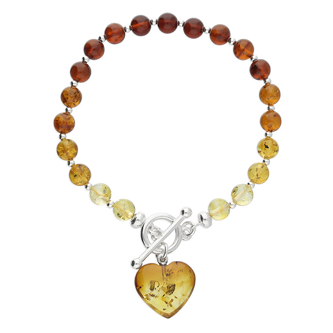 Cognac amber graduated bead bracelet in varying and graduated tones of amber fastened with sterling silver TBar clasp and dangling heart charm.