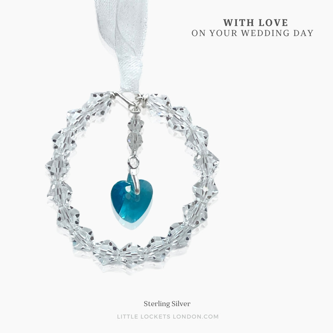 A circle of highest quality Austrian crystals surround an Austrian crystal blue heart. Suspended from white ribbon. A pretty something blue bouquet charm, shown mounted on card with the wording ofyour choice before being placed in a gift box.