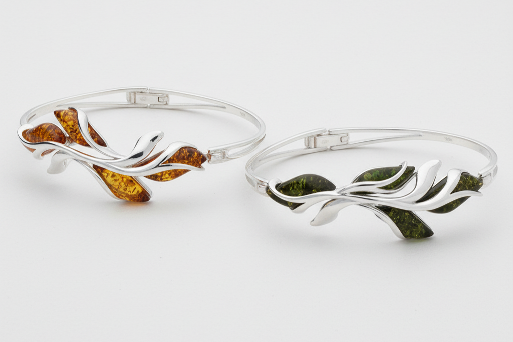 Two silver bangles with embedded amber and green stone on a white background