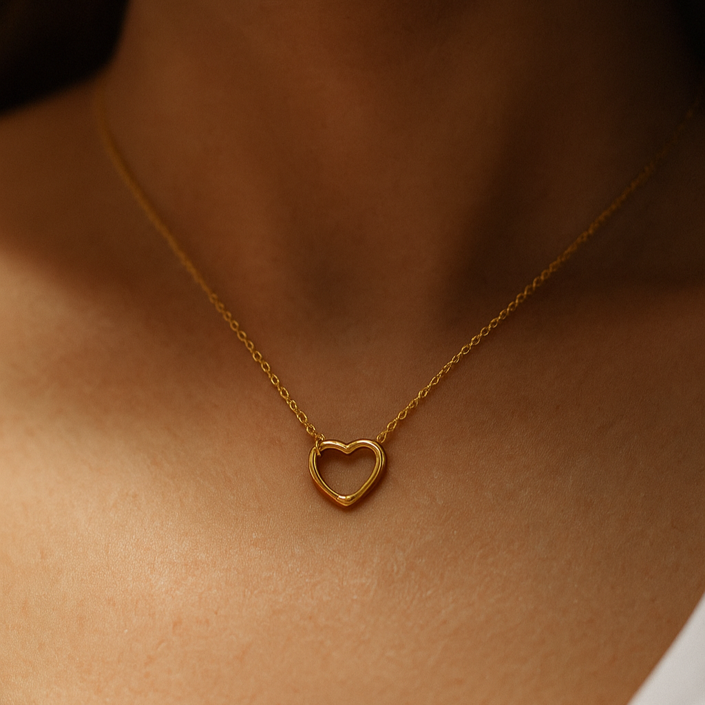 Gold heart-shaped necklace on a person's neck with a neutral background