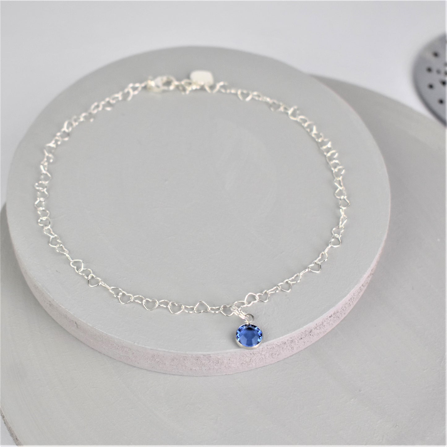 Sterling silver heart shaped links form this pretty anklet hung with a tiny blue crystal.