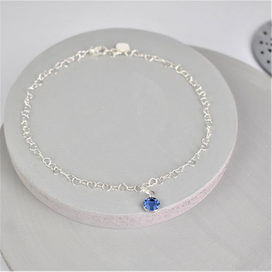 Sterling silver heart shaped links form this pretty anklet hung with a tiny blue crystal.