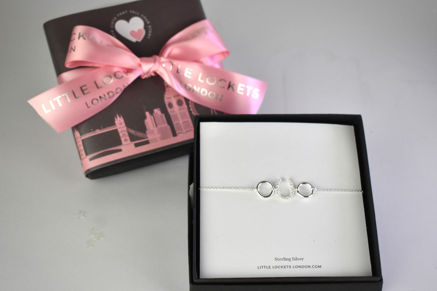 Sterling silver bracelet with cubic zircona horseshoe link. Adjustable by 1 inch extender.. Shown in gift box with luxury gift wrap upgrade in background.