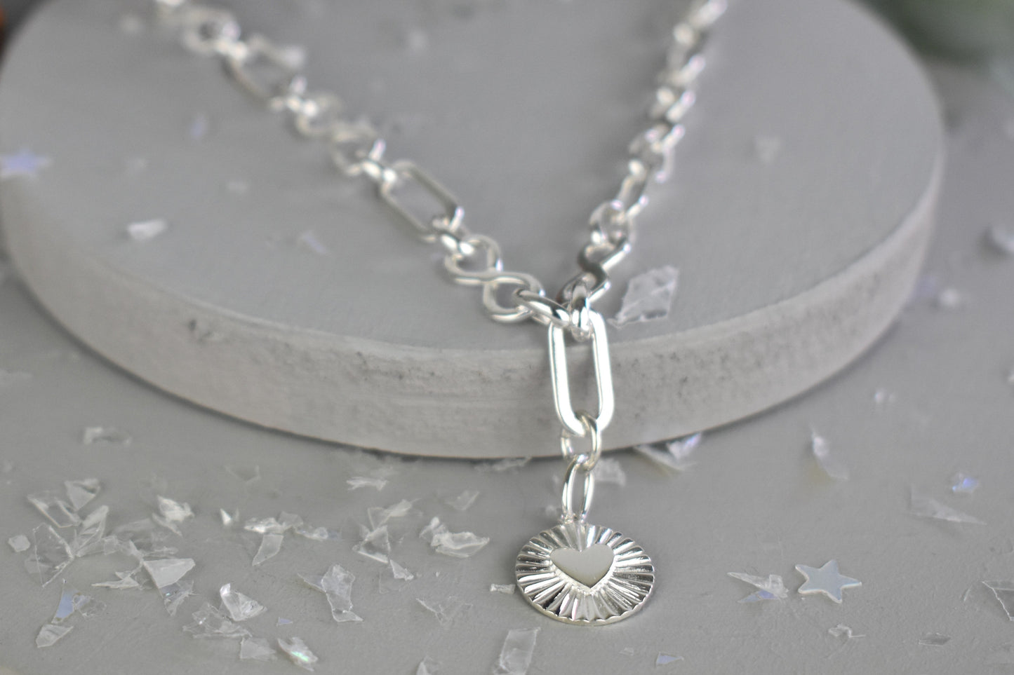 Sterling Silver Handmade Flat Link Infinity Necklace featuring a Heart Rays Pendant. Showcases flat oval and infinity links and features a Sterling Silver Sunburst Heart Rays charm pendant surrounded by an intricate sun rays design