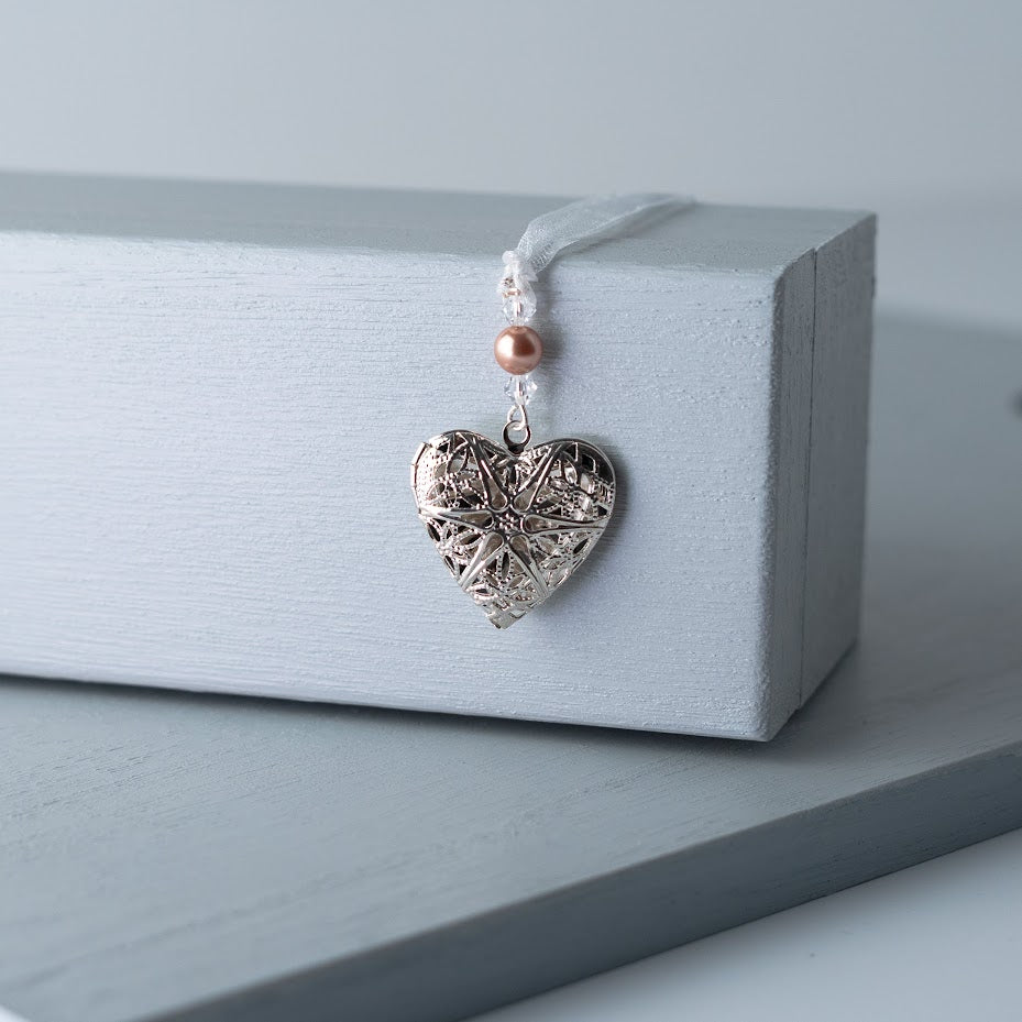Filigree locket opens to take one photo and is finished with crystals and a pearl or crystal in your wedding colours. The organza ribbon attached allows it to be fastened to a bouquet, corsage or handbag.