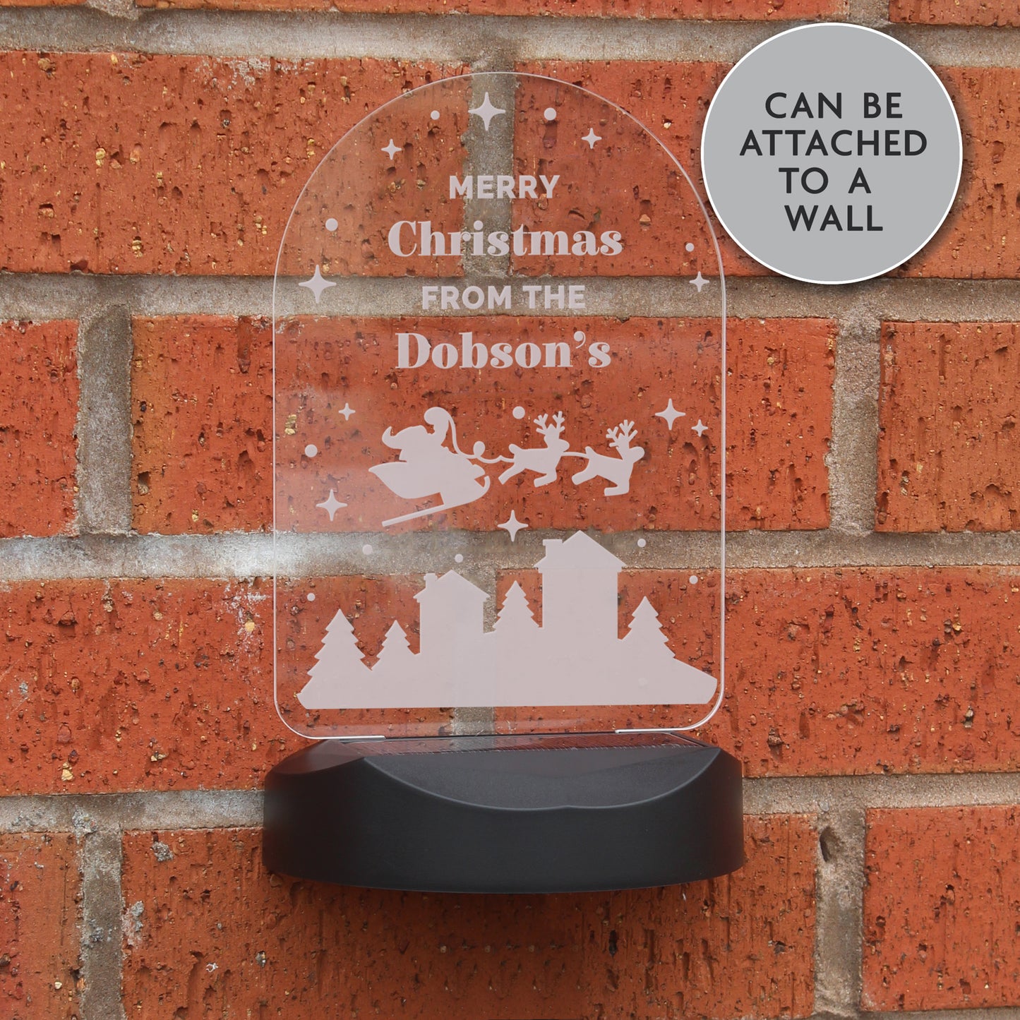 Solar powered outdoor Christmas light in arch shape showing Santa and his sleigh over rooftops. The light can be personalised with up to four lines of text in a message of your choice. Shown wall mounted