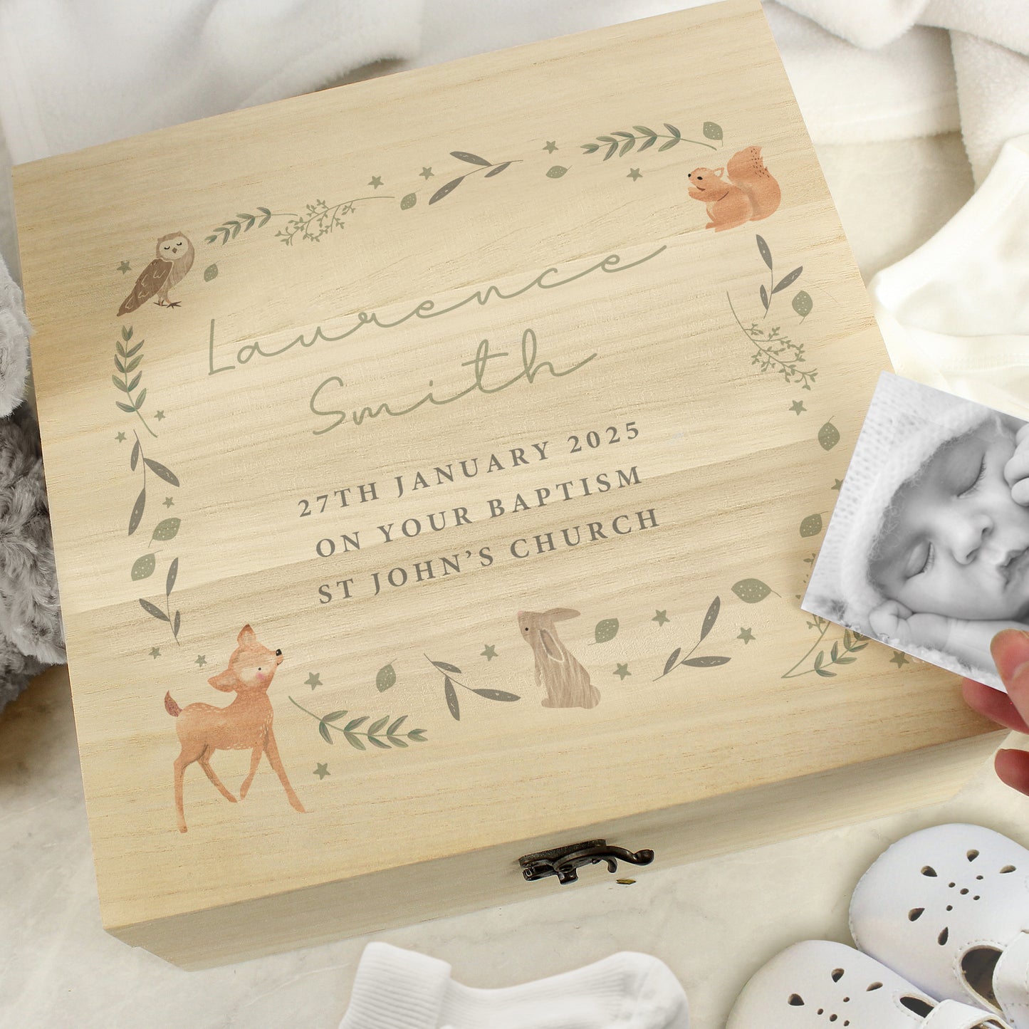 A wooden box with woodland animal and leaves forming a square. Within the square is five lines of personalised text, the first two in script font and the remaining three in block capitals. Fastened with a metal clasp.