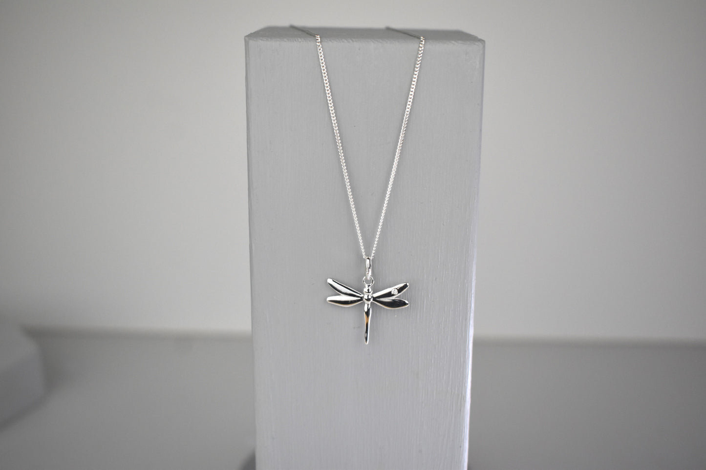 Dragonfly is sterling silver with a sparkling cubic zirconia crystal on its wing. Hangs on a 16 to 18 inch adjustable sterling silver chain.