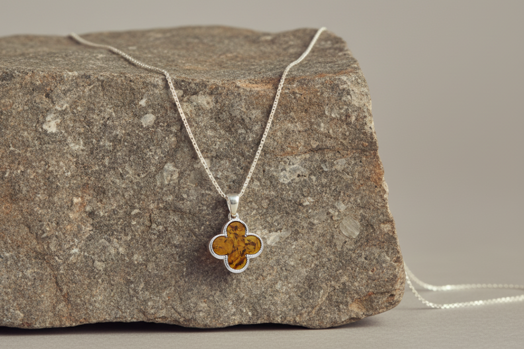 Quatrefoil-shaped pendant inlaid with genuine cognac amber. Finely textured Sterling silver edging. Pendant hangs from a sterling silver chain.