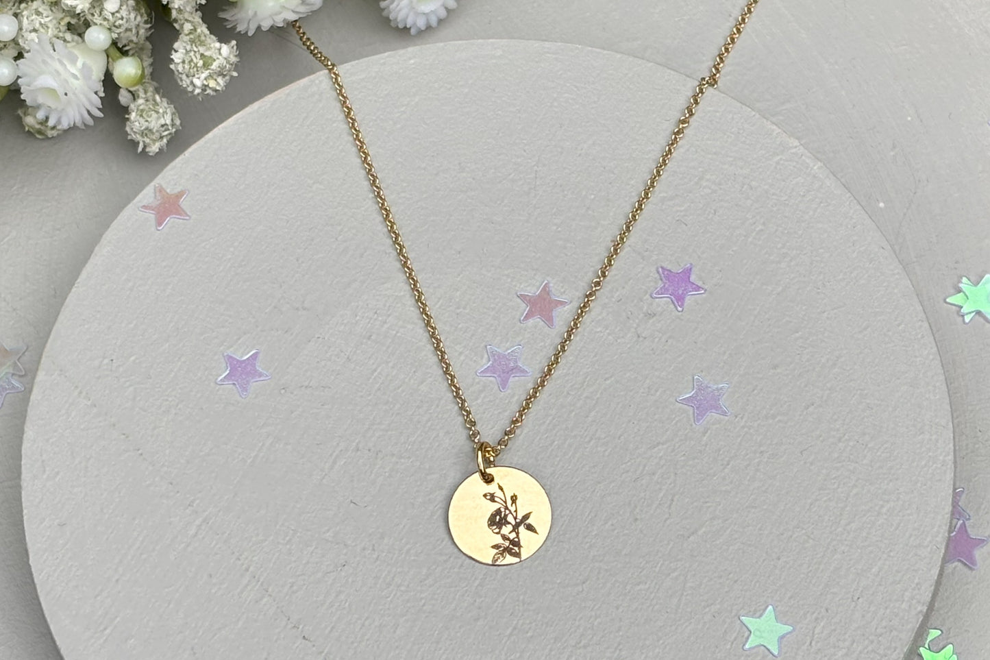 delicate Gold Filled Birth Flower Pendant. Crafted on an 11mm coin pendant, this simple piece is engraved with the intricate design of birth flowers on the front side and on the reverse side features a hidden personalised engraving, making it truly unique.