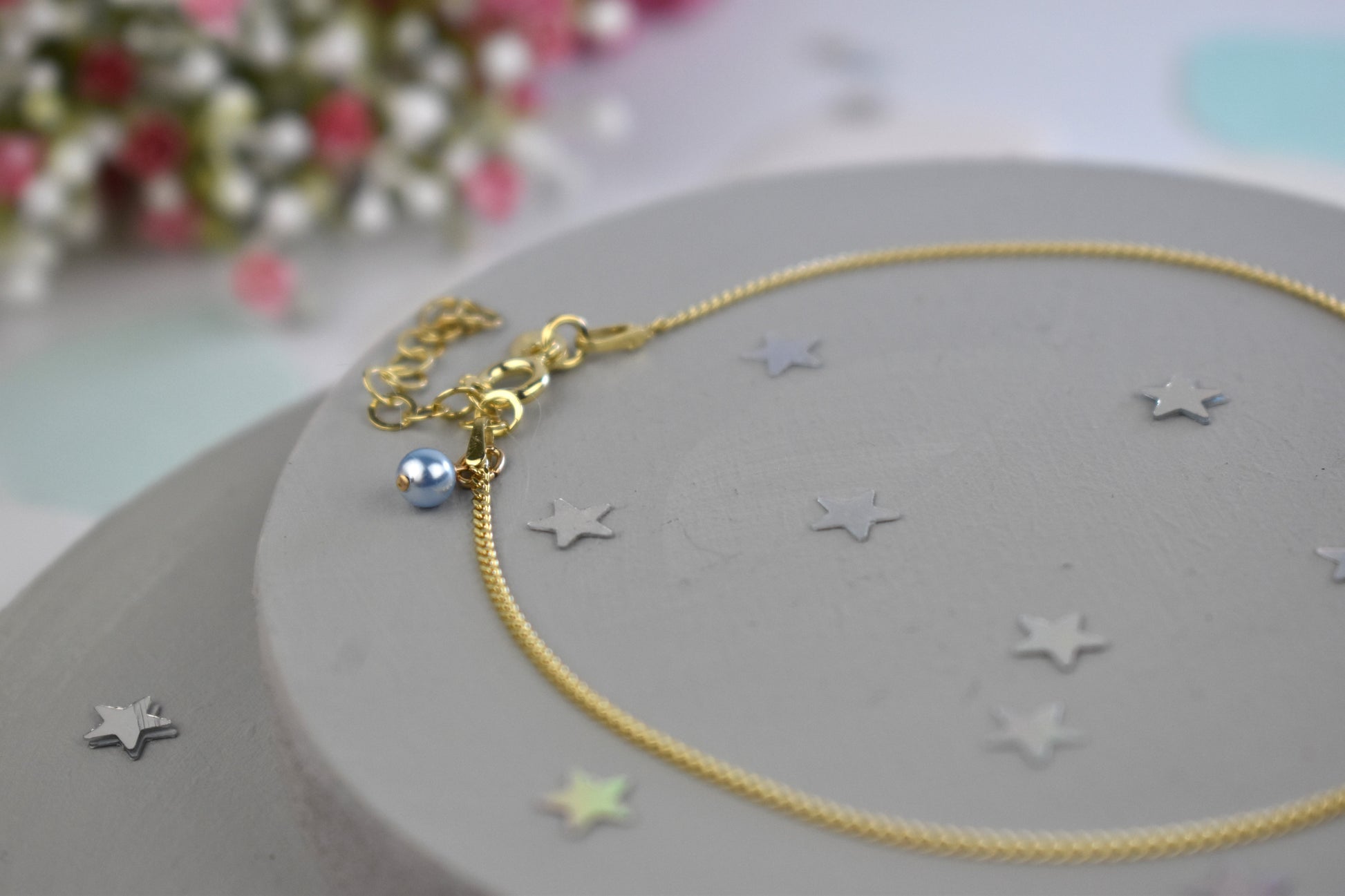 Close up of Gold-plated sterling silver anklet with delicate blue crystal