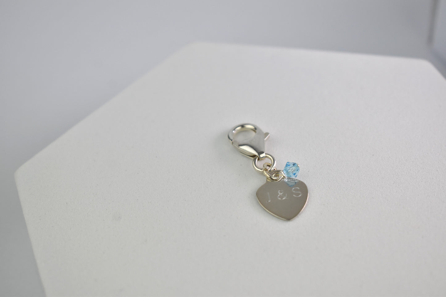 Sterling silver engraved heart and trigger clap with a tiny blue crystal. Something blue charm for a bouquet, shoe, garter or inside the gown