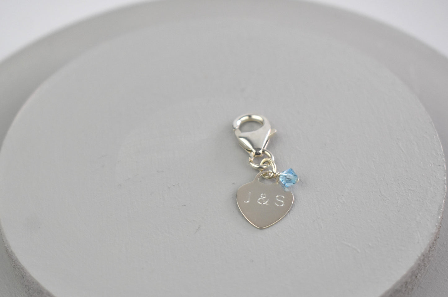 Sterling silver engraved heart and trigger clap with a tiny blue crystal. Something blue charm for a bouquet, shoe, garter or inside the gown