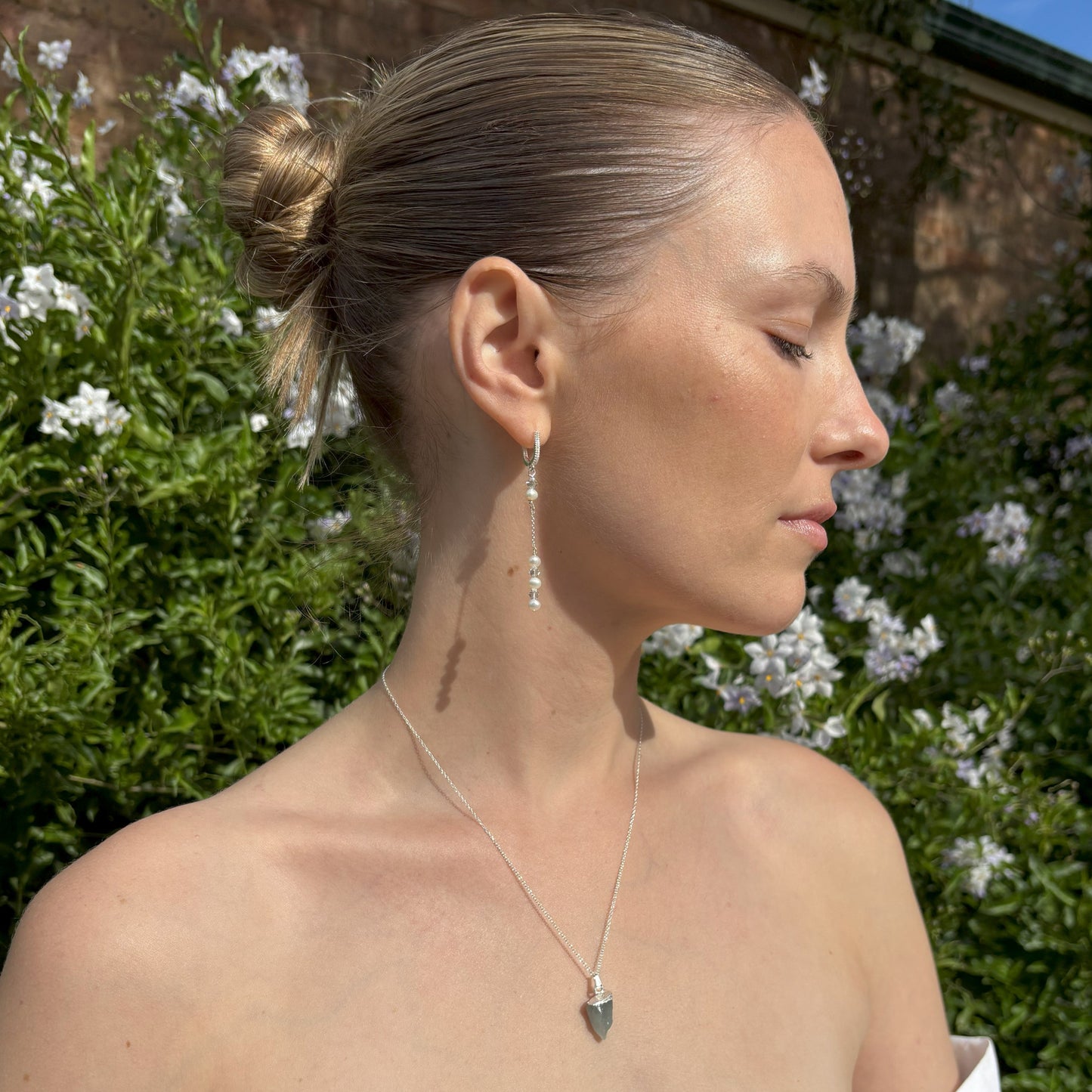 Raw Gemstone Pendant. The pendant has a sterling silver tip and is suspended from a sterling silver chain. It is mounted on card with the gemstone name and three of the properties of the crystal.