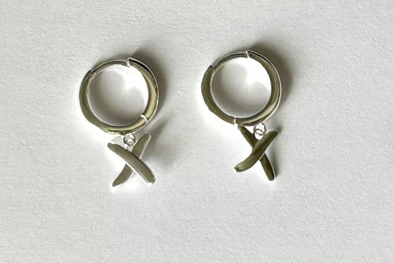 Huggie earrings to match our golden kisses necklace. 9mm huggies shown in sterling silver have a "kiss" dangling from each earring.