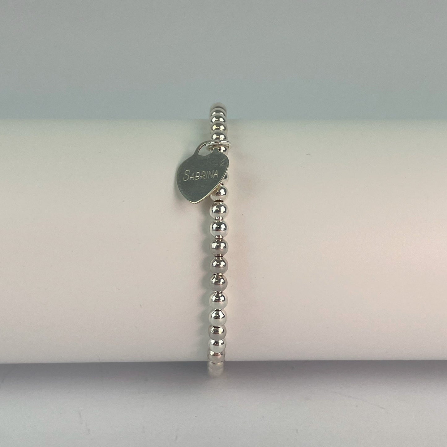 A beaded bracelet in your choice of 4mm sterling silver or silver plated beads, with a sterling silver heart engraved to your choice.