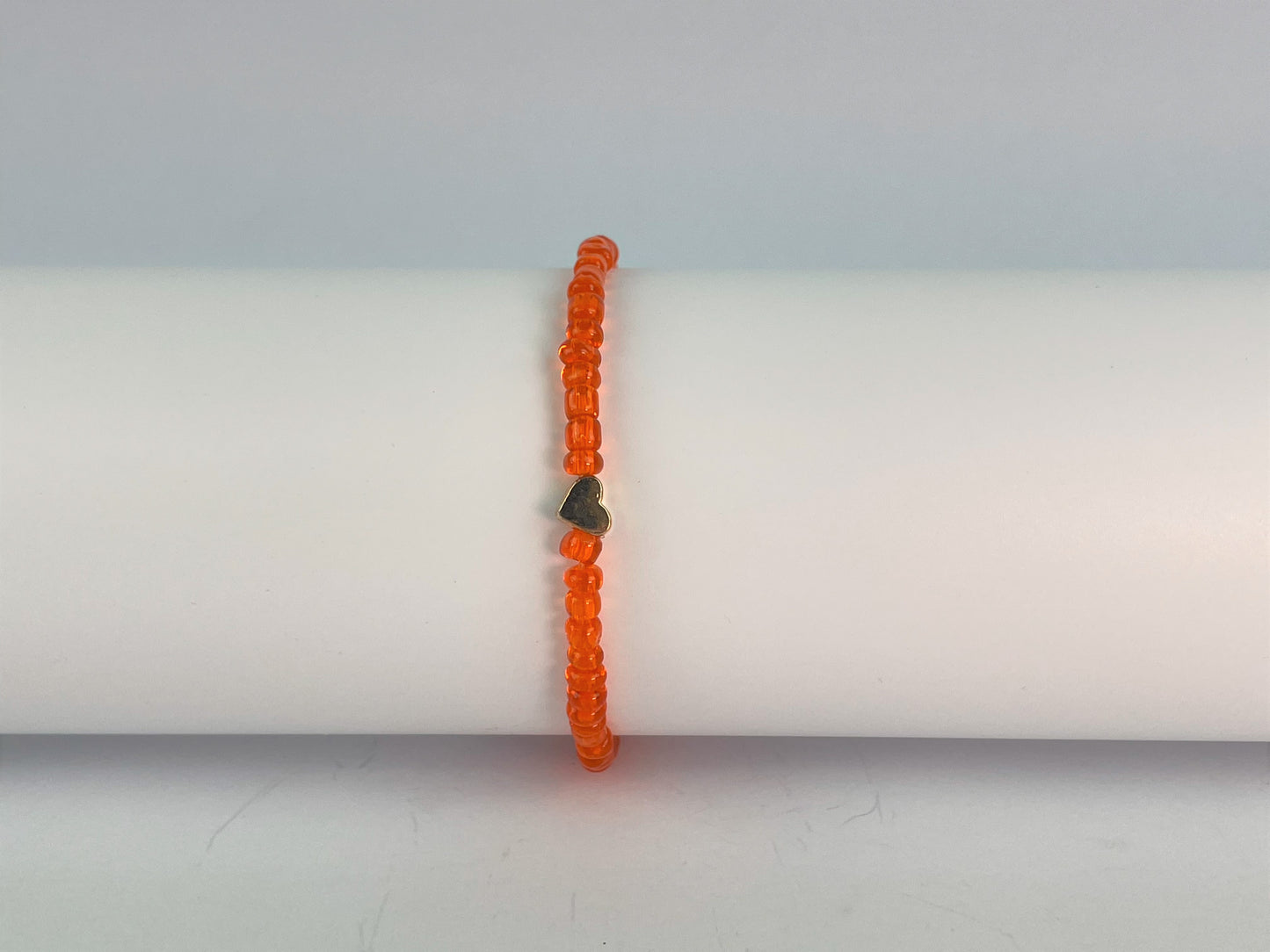 fiery orange glass beads form an elasticated bracelet finished with a gold plated heart bead.