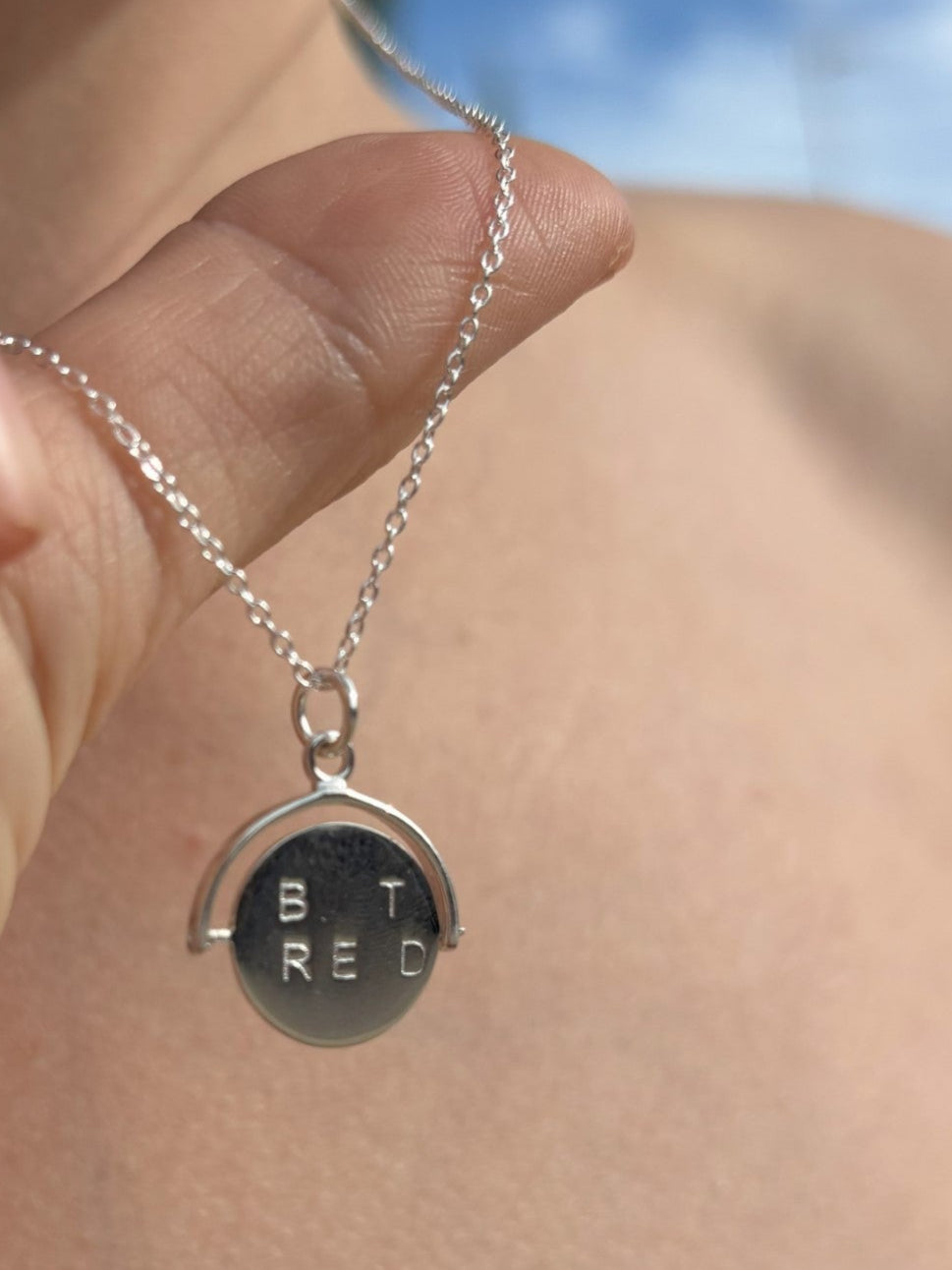 Sterling silver spinner necklace with lettering either side. When spon is forms the words "Best Friend"