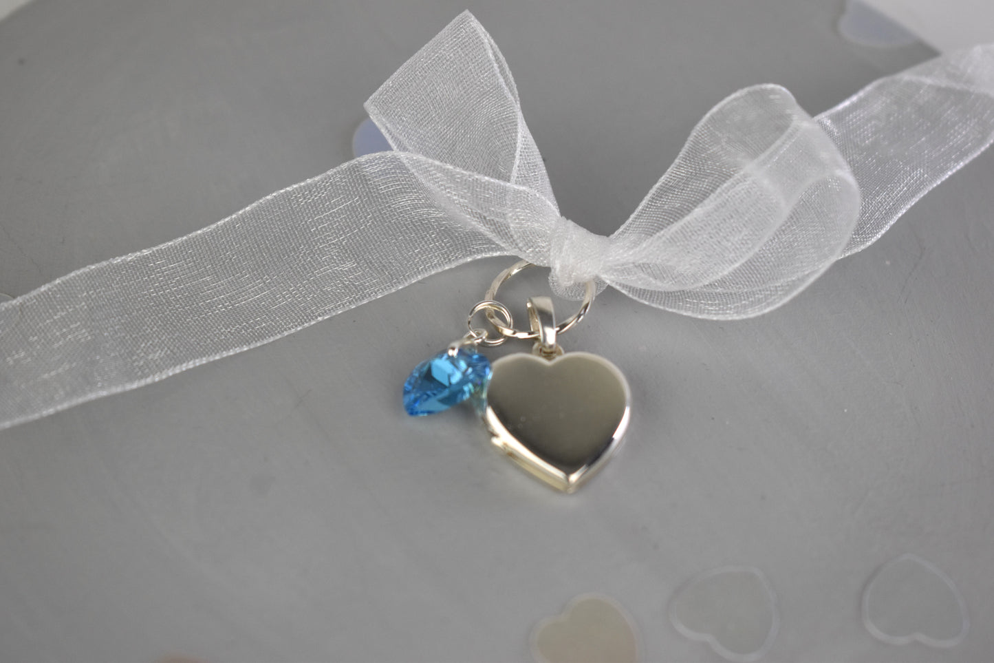 sterling silver heart shaped locket for two photos, accompanied by a blue crystal heart and threaded through a sterling silver loop. Ribbon supplied for you to attach to your bouquet. Easily detach the locket later to wear with a chain.