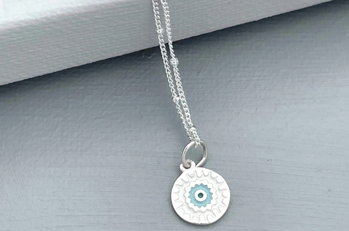 sterling silver Mandala charm with blue enamel hangs on a sparkling sterling silver satellite chain finished with a spring ring clasp.