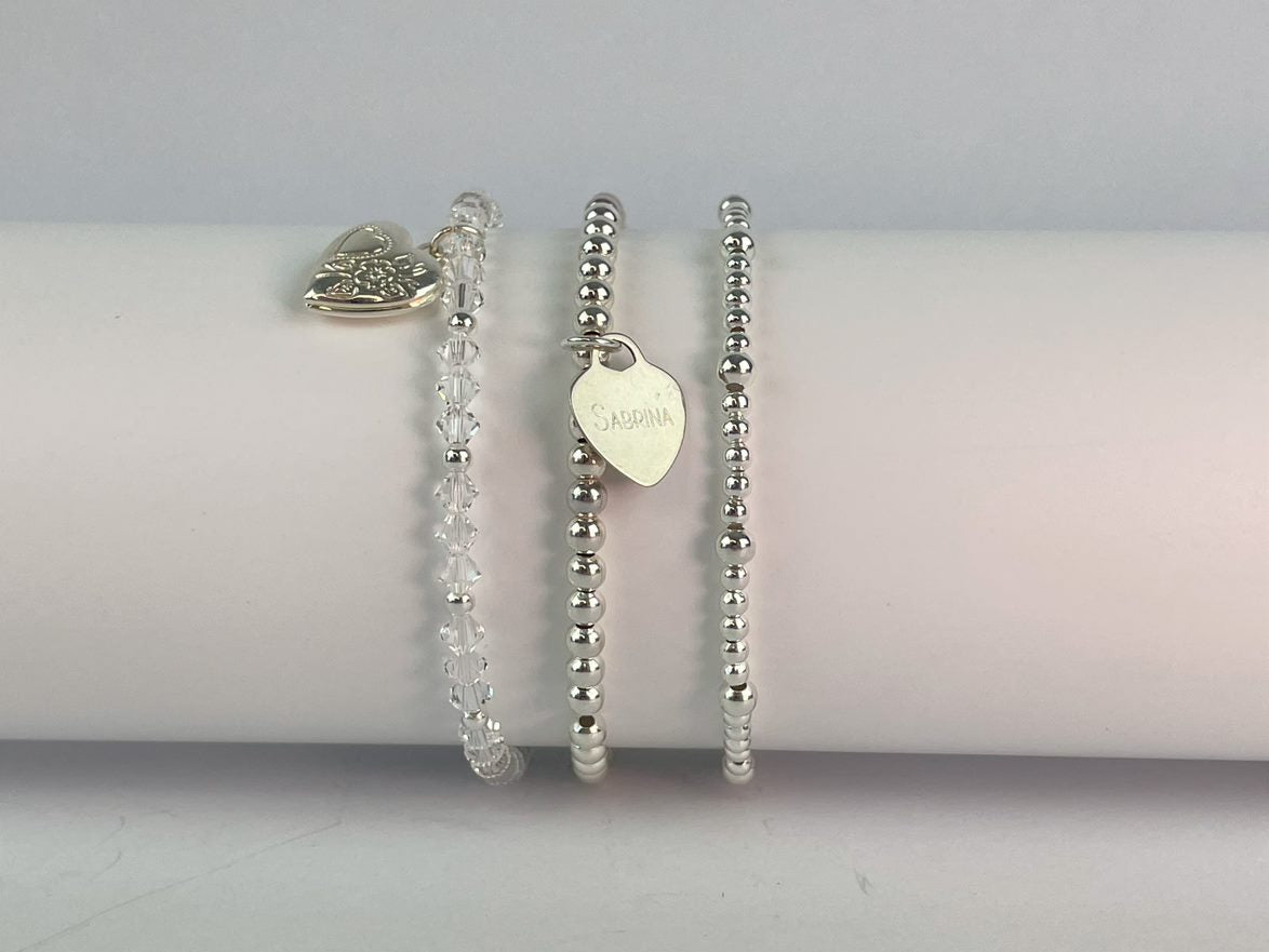 A beaded bracelet in your choice of 4mm sterling silver or silver plated beads, with a sterling silver heart engraved to your choice.. Shown with a crystal heart bracelet and beaded bracelet using 3mm and 4mm beads.