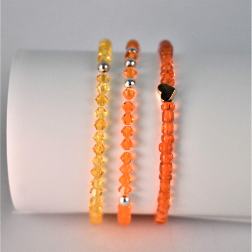 orange crystal bracelet is teamed with matching yellow crystal and fiery orange bracelets for a bracelet stack