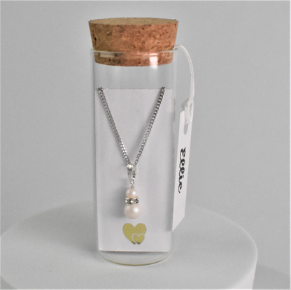 Double pearl drop pendant on silver chain is contained within a glass bottle with a scroll bridesmaid request. Bottle is finished with label showing bridesmaid's name