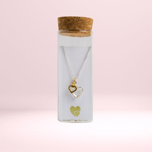 Message in a Bottle jewellery. A sterling silver heart is twinned with a smaller gold vermeil heart and suspended from a 16-18" sterling silver chain. The necklace is placed in a small glass bottle that includes a scroll  for you to write your own message.