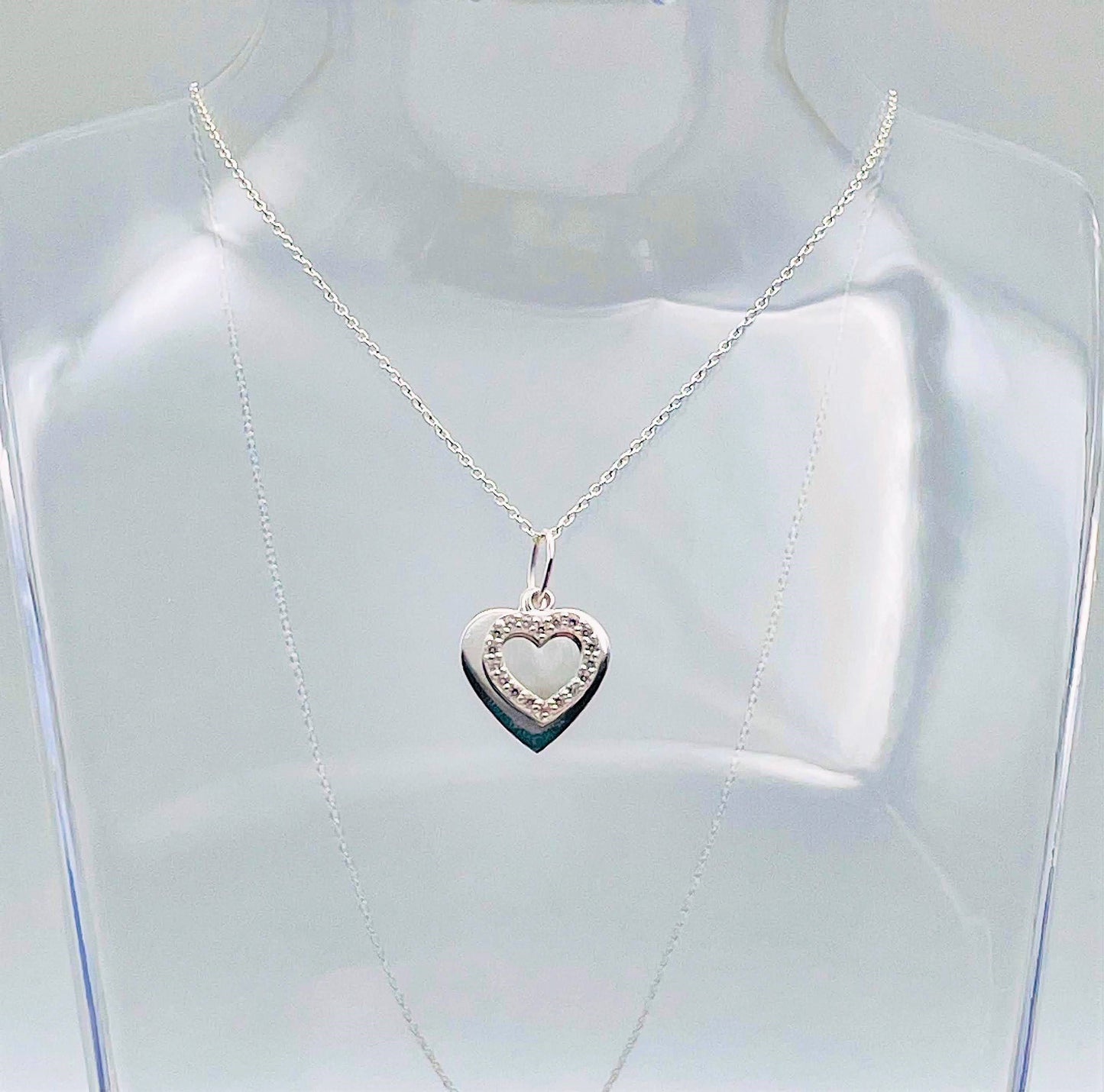 A sterling silver solid heart sits behind an outline heart with cubic zircona and suspended from a sterling silver chain. Your necklace arrives in a small glass bottle with a scroll for you to add your own message.