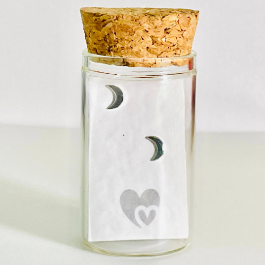 sterling silver crescent moon studs in a glass bottle with cork lid. Bottle also includes a parchment scroll for you to write your own message.