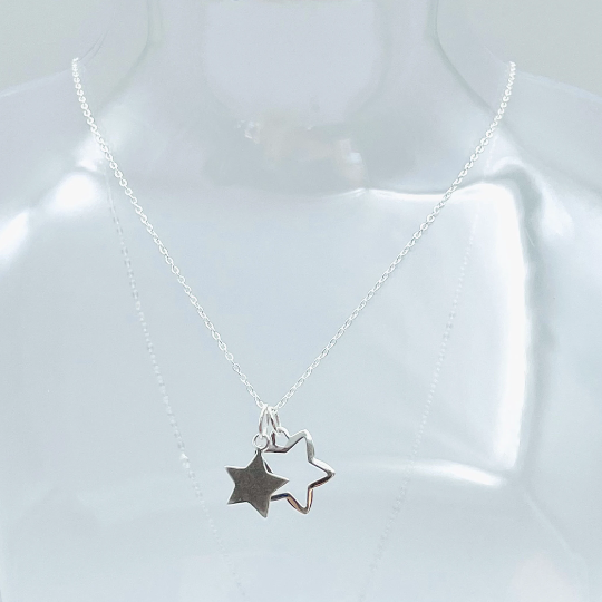 Two sterling silver stars, one solid, one outline hung from a sterling silver pendant and placed in a glass bottle. Part of the Message in a Bottle range.
