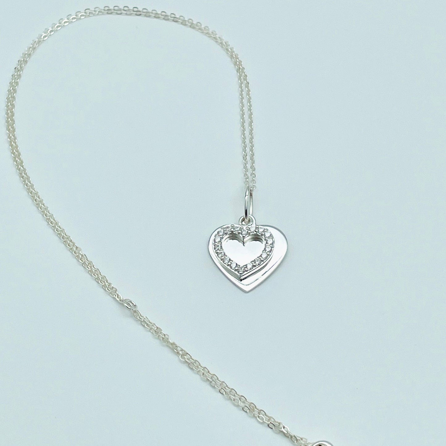 two hearts, one sterling silver and the other an open heart of cubic zircona hung from a sterling slver chain