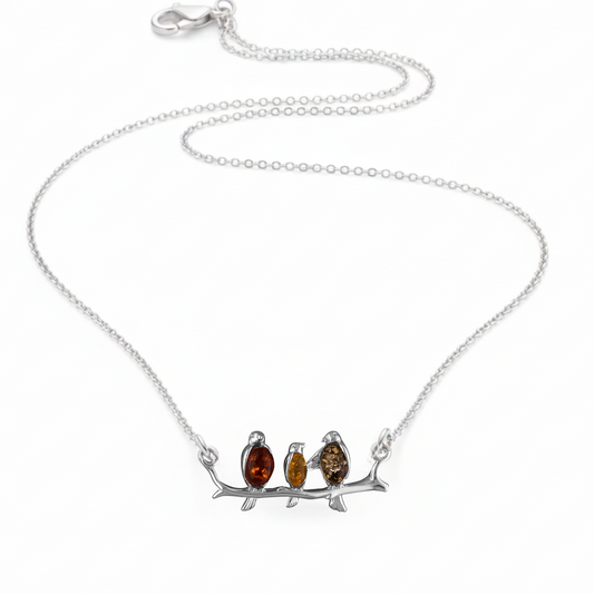 Sterling silver connector necklace showing three birds on a branch. The birds are inlaid with three types of amber - honey, cognac and olive. 