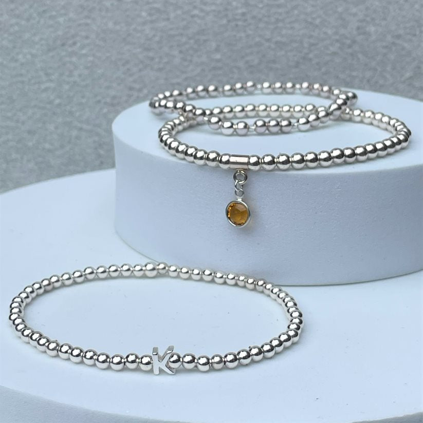 our silver initial bracelet shown with the silver beaded bracelet and birthstone bracelet