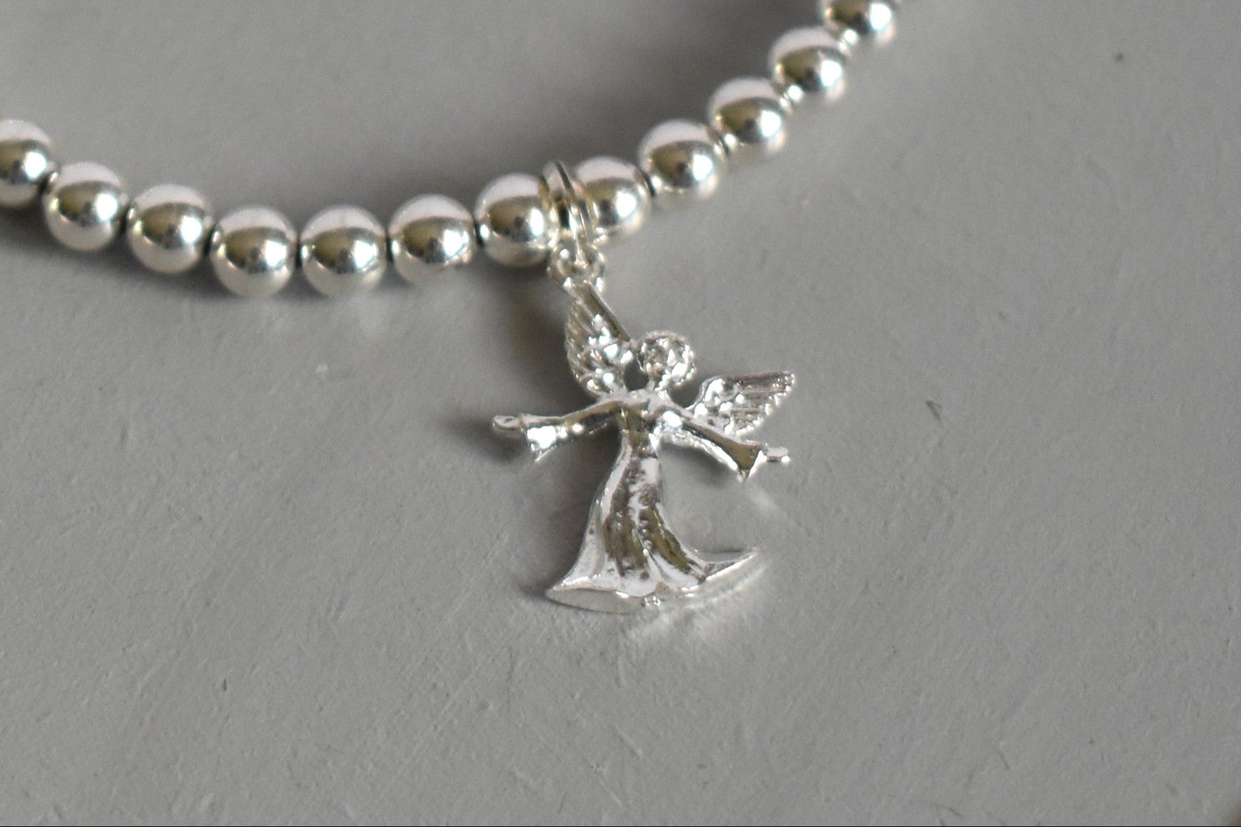 Sterling silver beaded bracelet with 4mm beads and a 16mm sterling silver angel charm. Close up of charm
