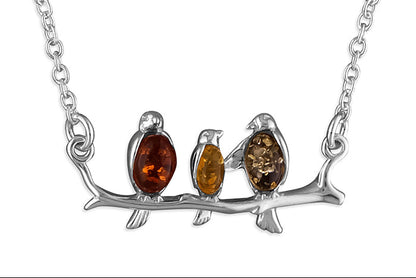 Sterling silver connector necklace showing three birds on a branch. The birds are inlaid with three types of amber - honey, cognac and olive.