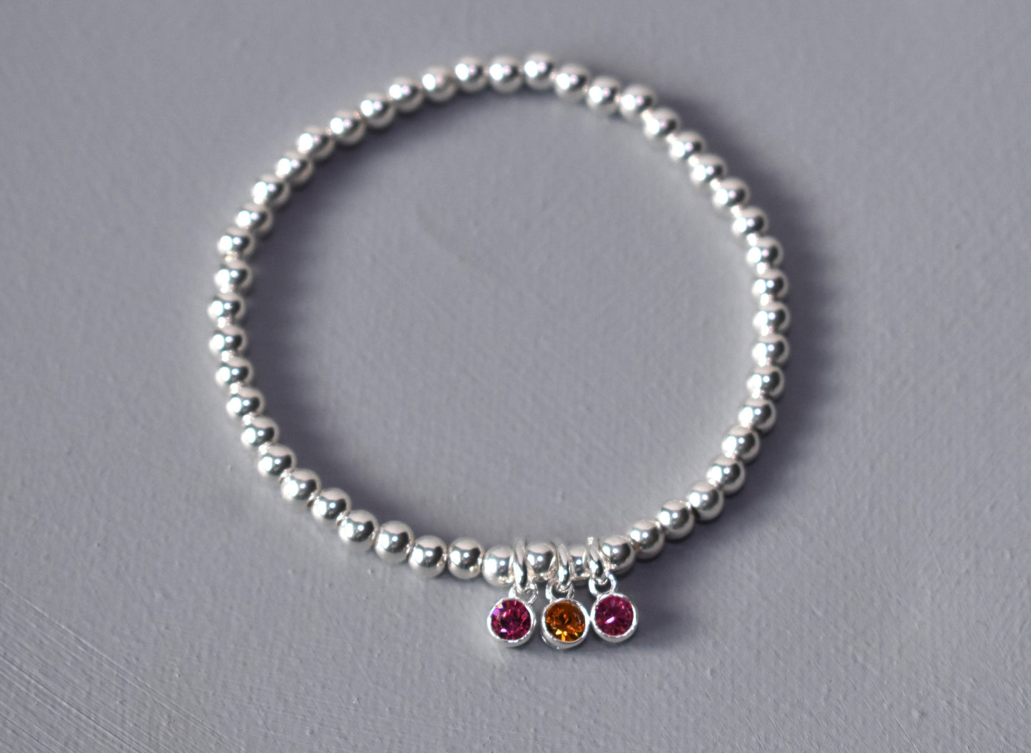 Sterling silver beaded bracelet of 4mm beads threaded onto strong elastic with three birthstones. Up to five birthstones can be added to this bracelet