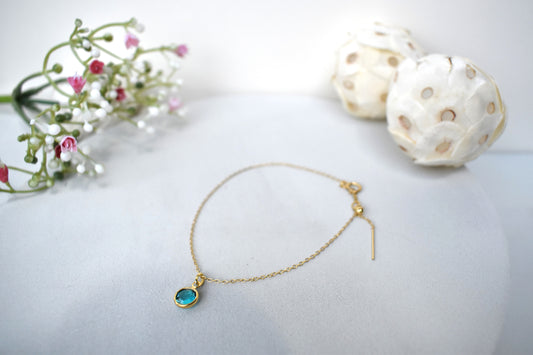A gold filled chain is  threaded through a bead to make this delicate bracelet adjustable. Finished with a birthstone of your choice, ths bracelet is the perfect summer accessory.