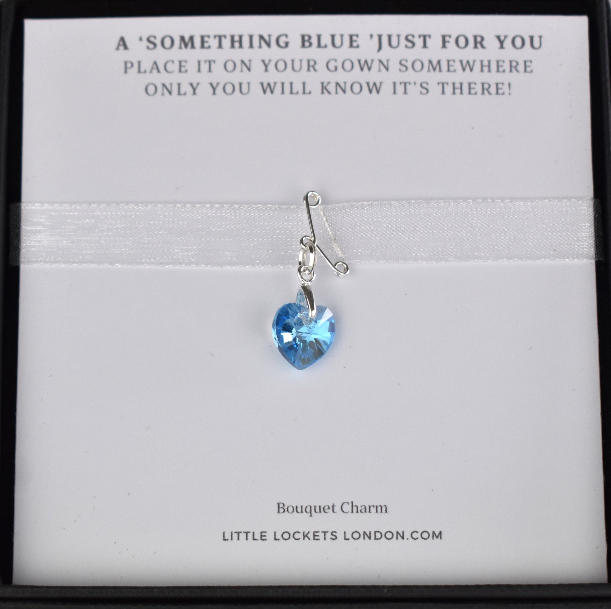 A tiny sterling silver pin holds a suspended blue crystal heart to form a secret something blue. Mounted on card with the rhyme "A something blue just for you, place it on your gown somewhere, only you will know it's there!