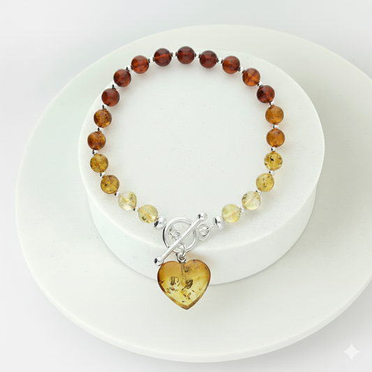 Cognac amber bracelet fastened with sterling silver TBar clasp and dangling heart charm. 
