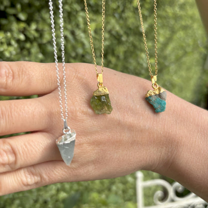 Collection of Raw Crystal Pendants. The pendants have a sterling silver tip or a gold plated sterling silver tip and are suspended from a chain. It is mounted on card with the gemstone name and three of the properties of the crystal. 