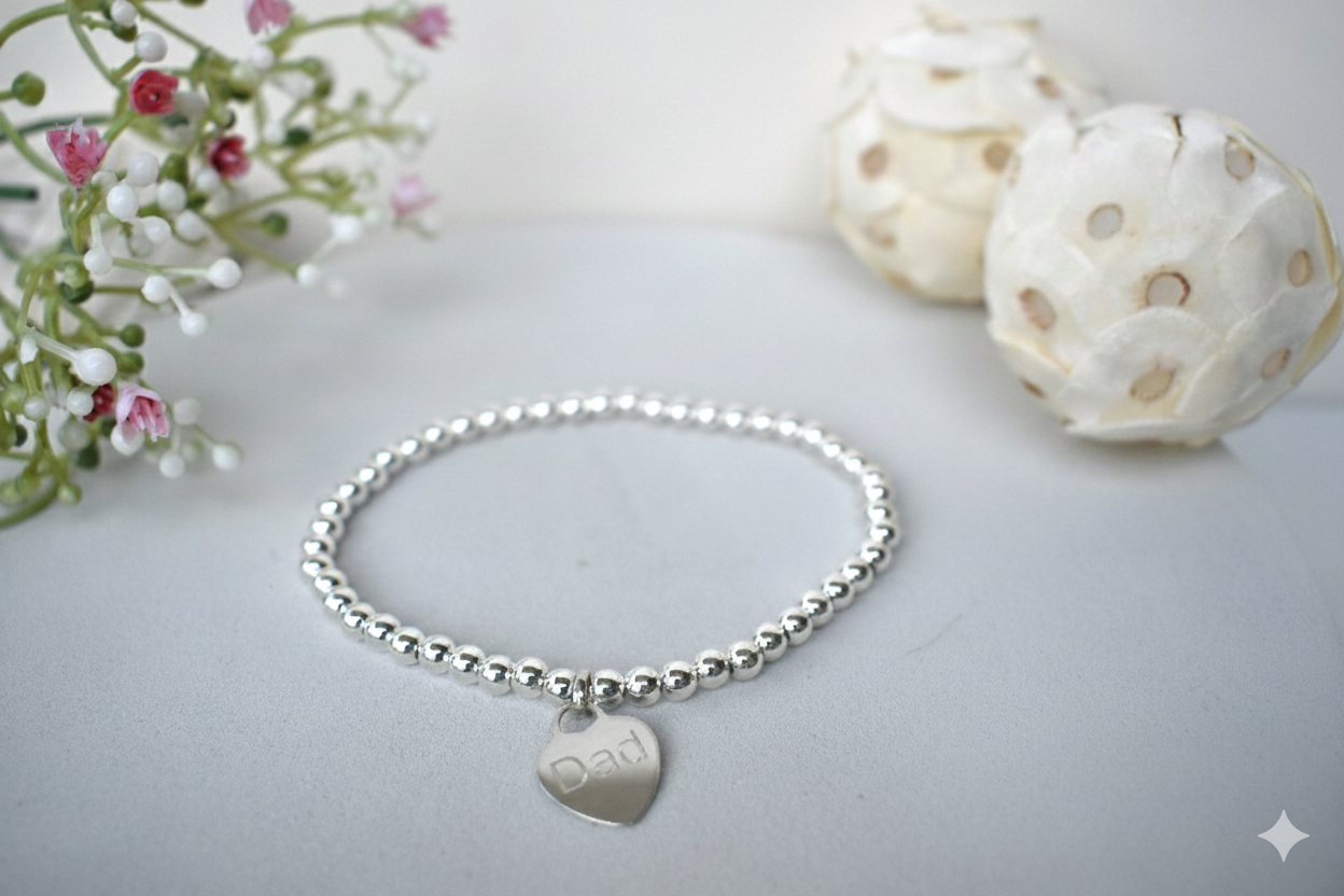 Silver beaded bracelet  of 4mm sterling silver beads threaded on strong elastic with a suspended sterling silver heart that can be engraved with wording of your choice. 