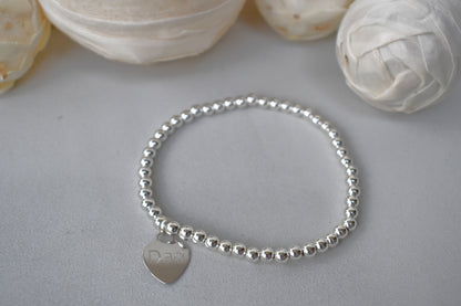 Personalised silver beaded elastic bracelet with engraved sterling silver heart charm, custom name or date, sterling silver shown