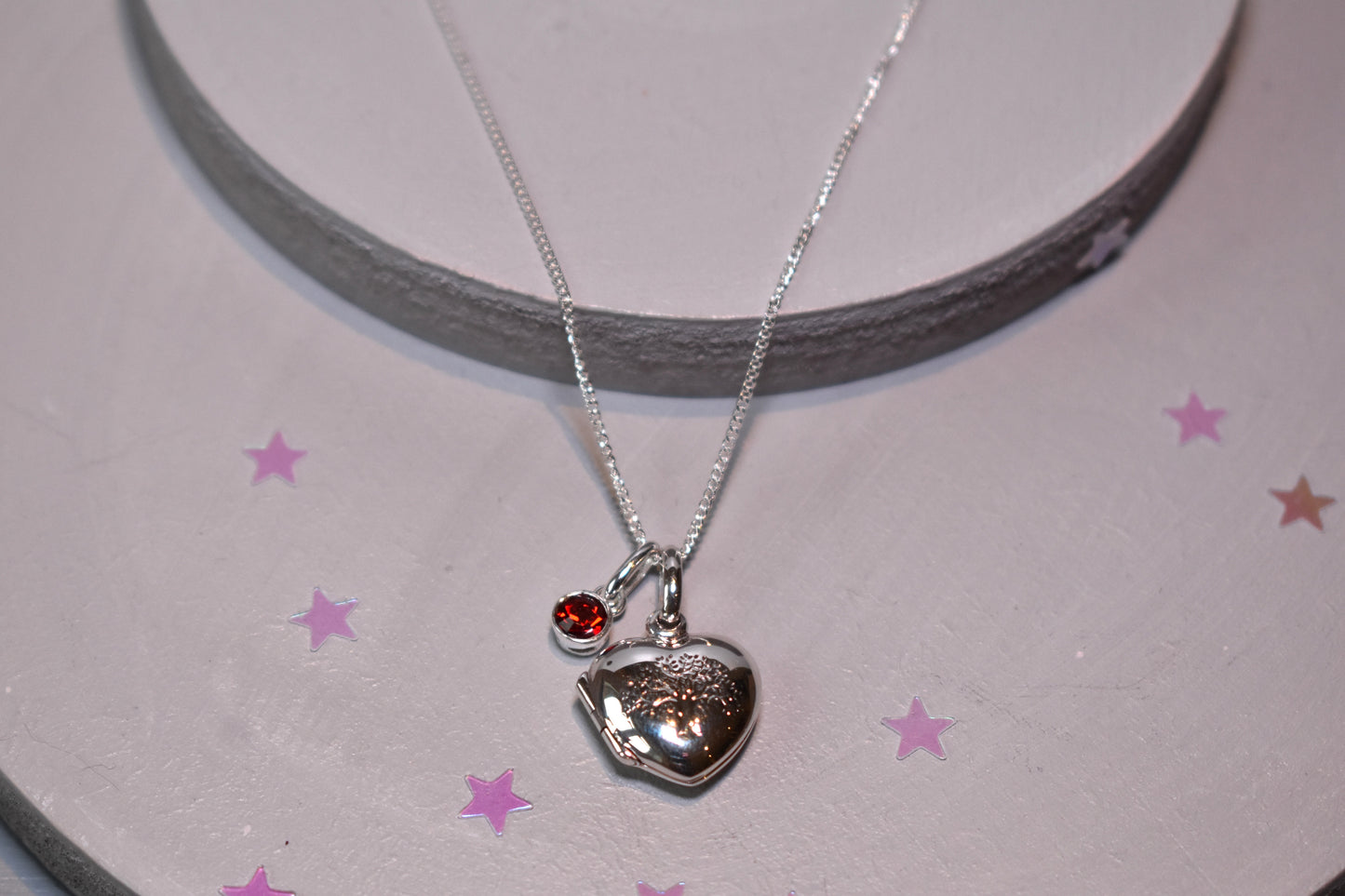 Sterling silver heart shaped locket with engraved family tree on the front. Opens to show space for two photos. Shown on an adjustable 16-18 inch sterling silver chain and with an optional birthstone.