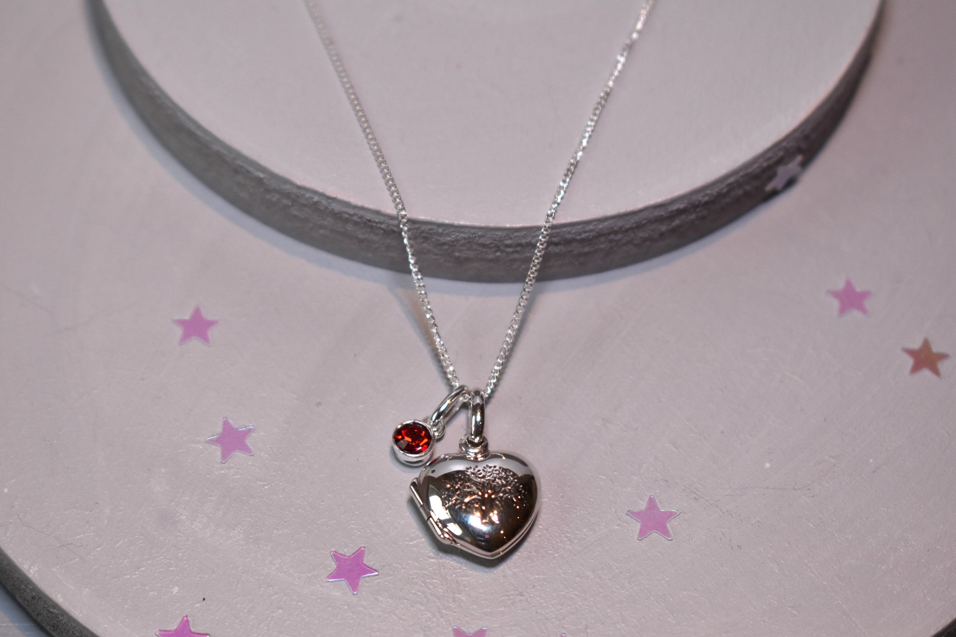 Sterling silver heart shaped locket with engraved family tree on the front. Opens to show space for two photos. Shown on an adjustable 16-18 inch sterling silver chain and with an optional birthstone.